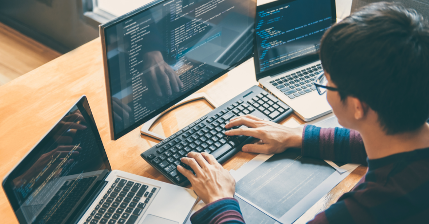 IT professional analyzing computer data on three monitors