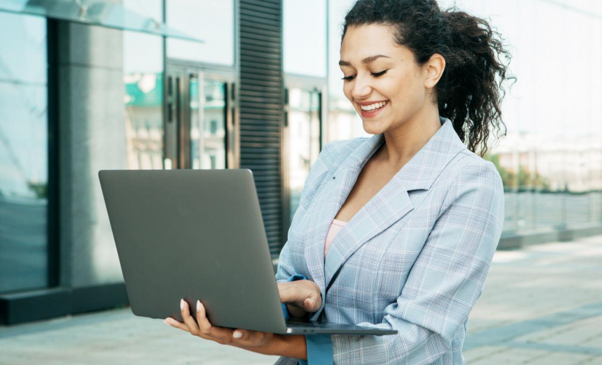 female professional uses her laptop outside an office building