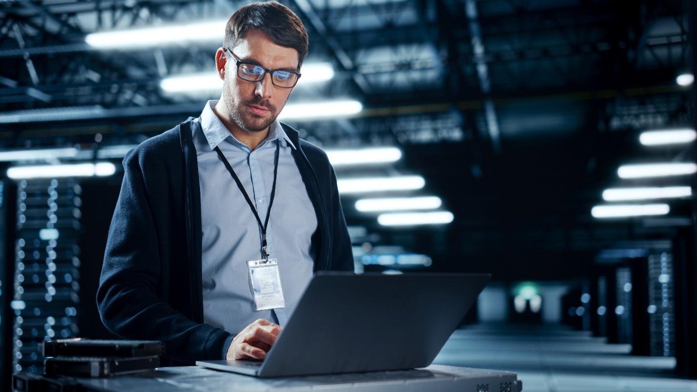 A male IT professional working in a data center.