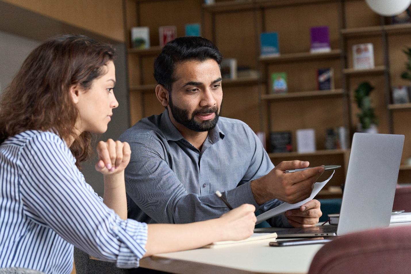 An employee teaching another employee about cybersecurity best practices and safety.  