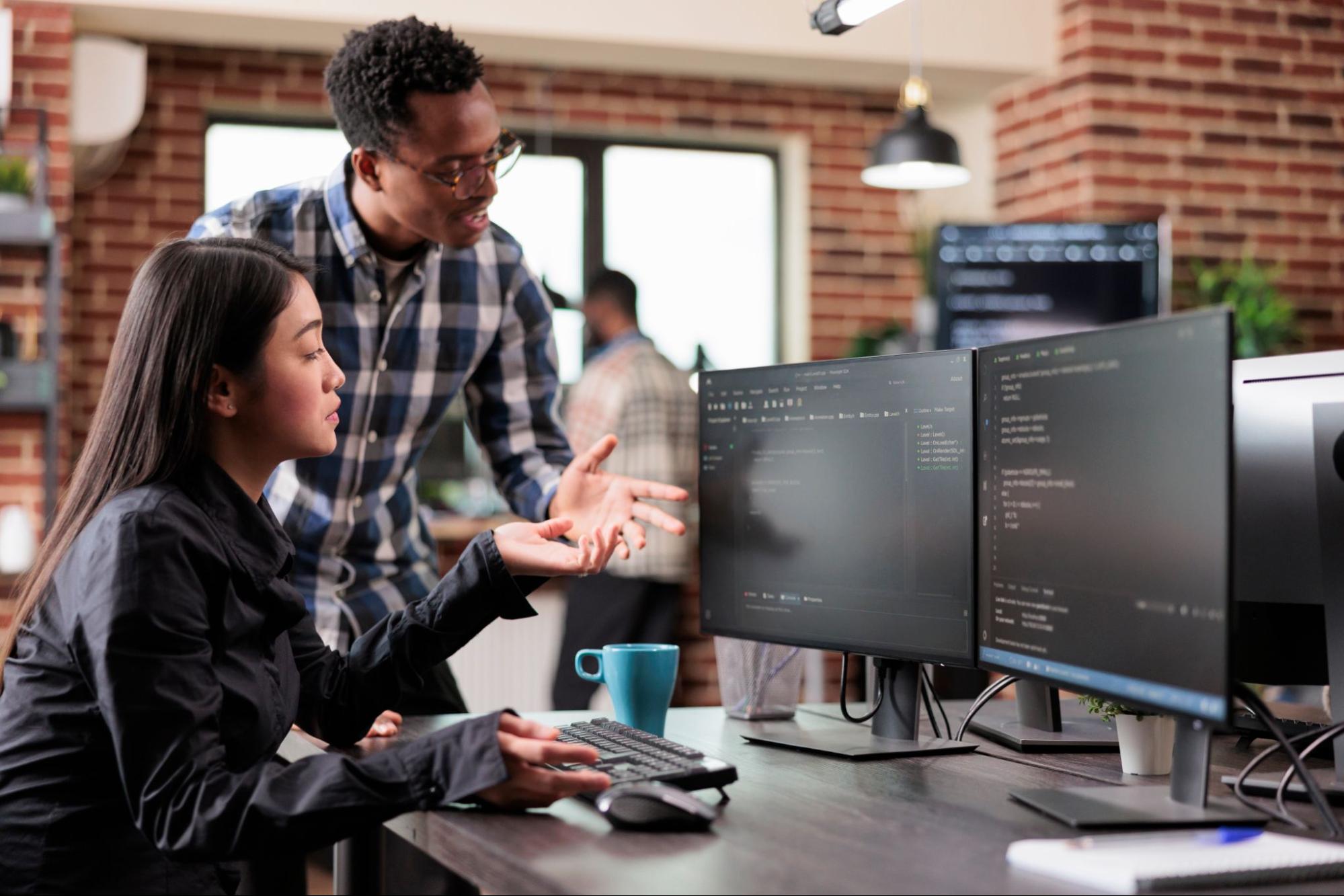 Two professionals at a computer examining system process details.