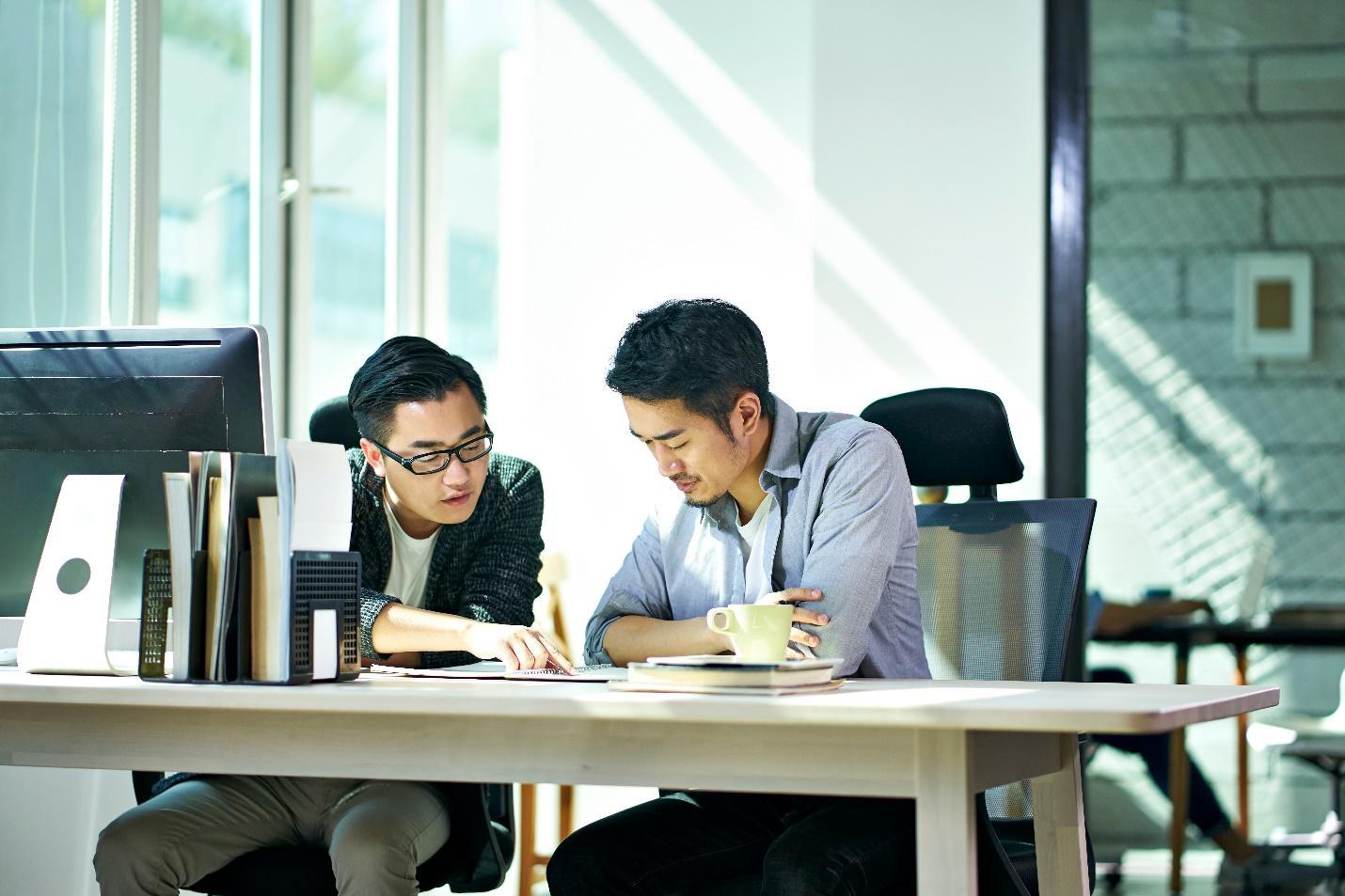 Two men reviewing cybersecurity protocols at a corporate office. 