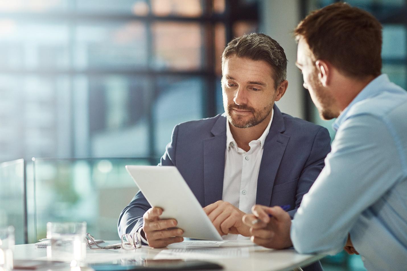 Two business people looking at a tablet during a meeting.