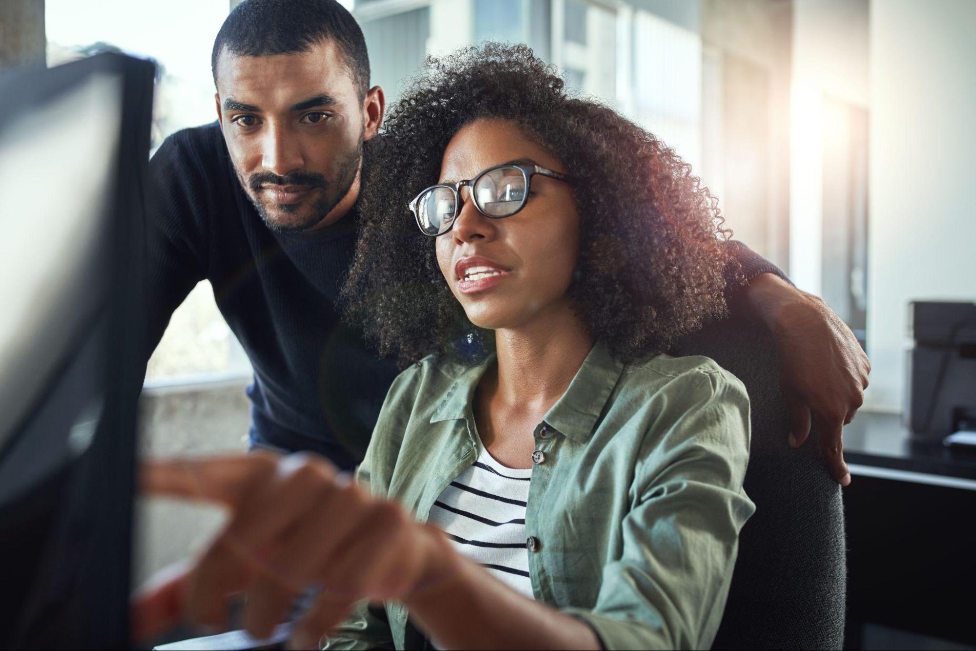 A young man and woman working together at a computer.