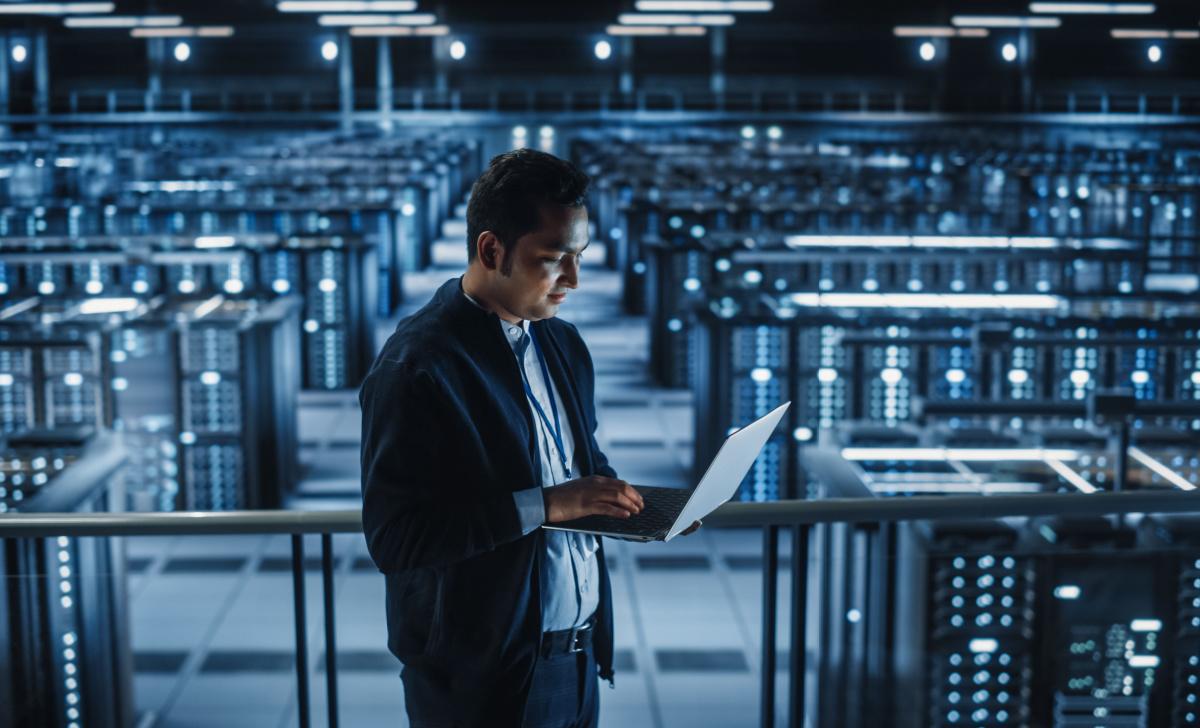 IT professional monitoring the health of a server room from his laptop dashboard.