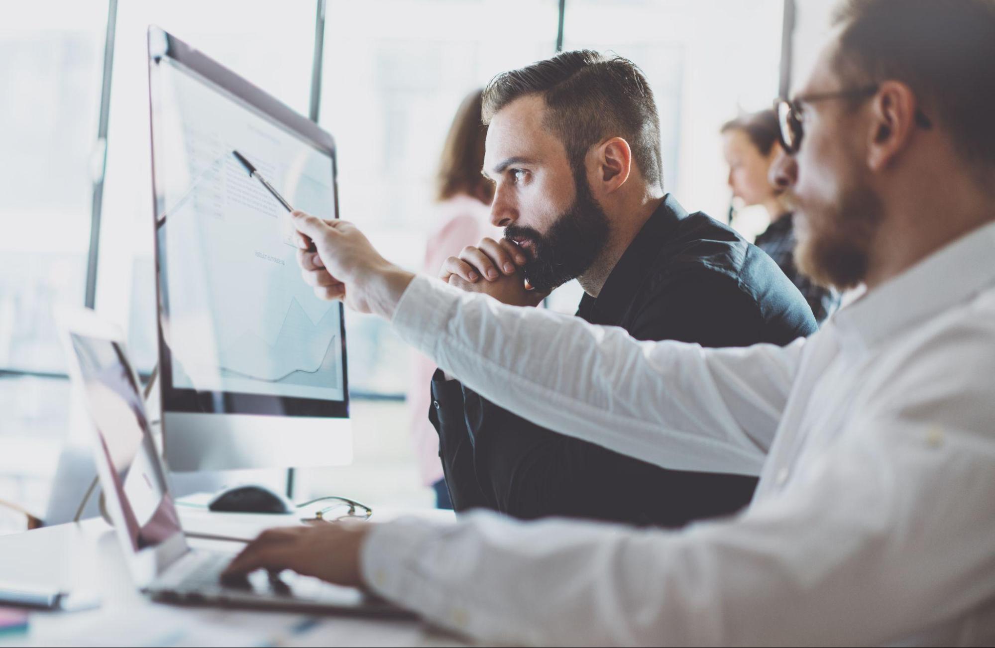 Two focused professionals deep in thought while working at a computer.