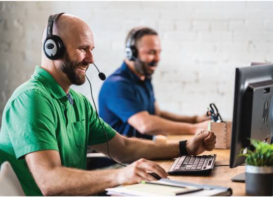 two it support technicians typing on keyboards speaking on headsets