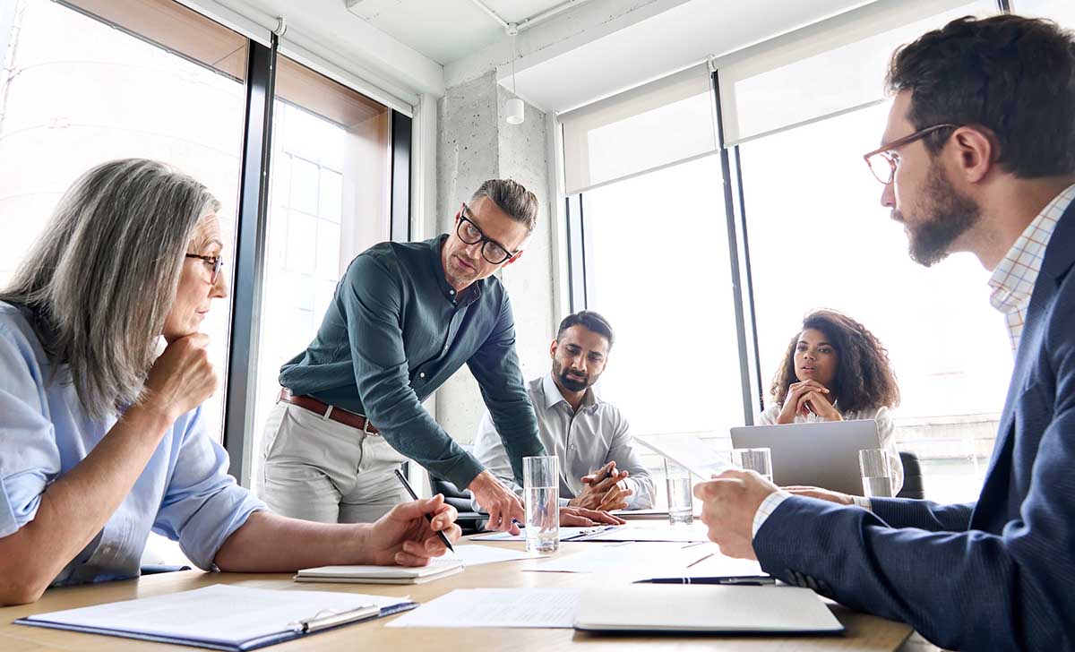 Coworkers huddled around a desk working on a business plan