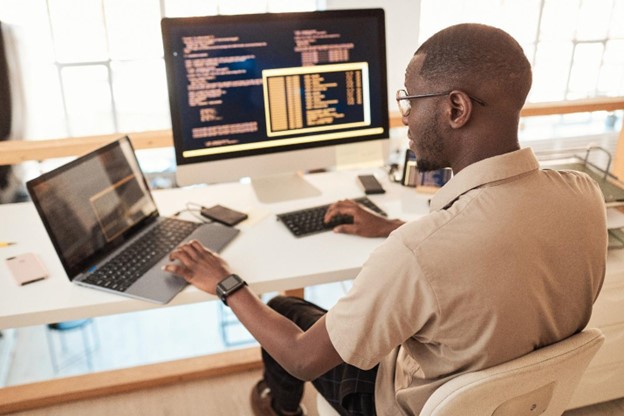 An IT professional working at two computers.