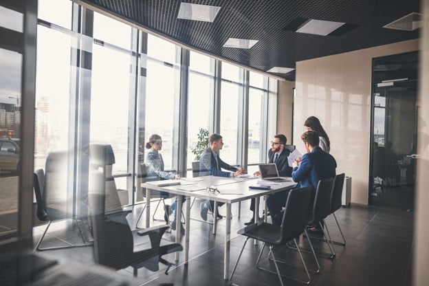 Employees sit around a conference table in a meeting.