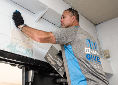 Man wearing gloves and cleaning a wall with a sponge