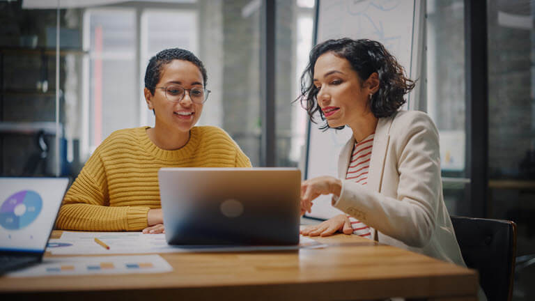 two people looking at a laptop screen